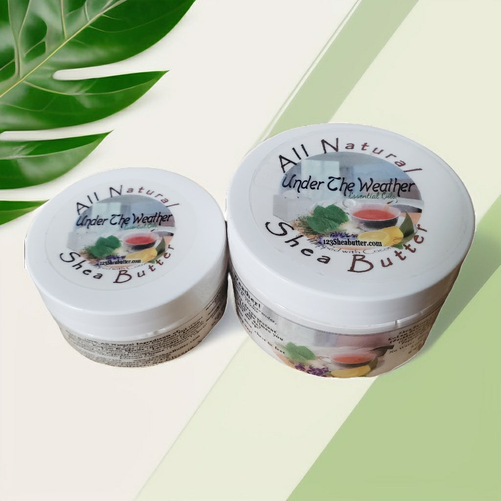 Two containers of All Natural Under The Weather Shea Butter on a light green background with leaves.
