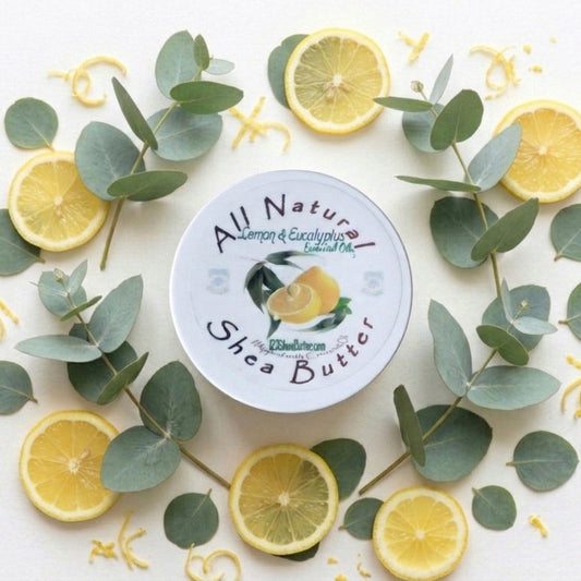 Jar of All Nature Shea Butter surrounded by lemon slices and eucalyptus leaves on a white background