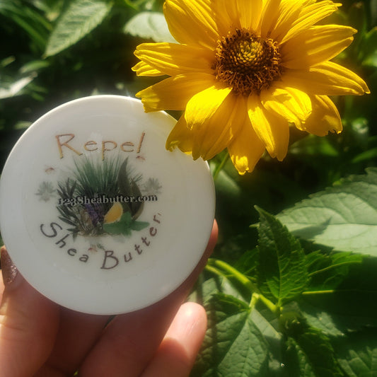 Hand holding a Repel shea butter travel size  with a yellow flower in the background