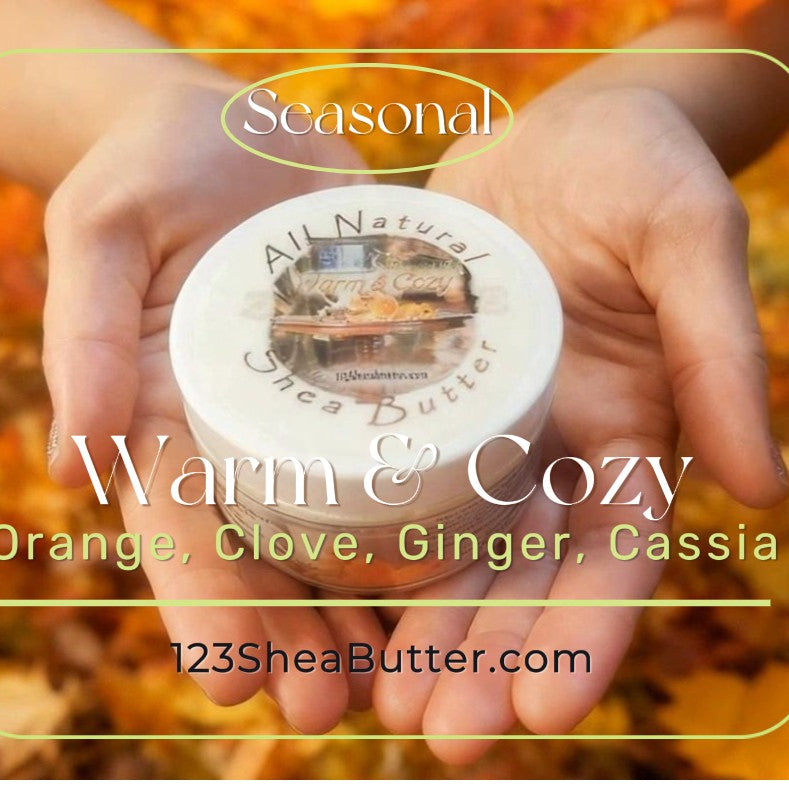 Jar of Warm and Cozy shea butter held in hands with autumn leaves in the background, featuring '123SheaButter.com'.