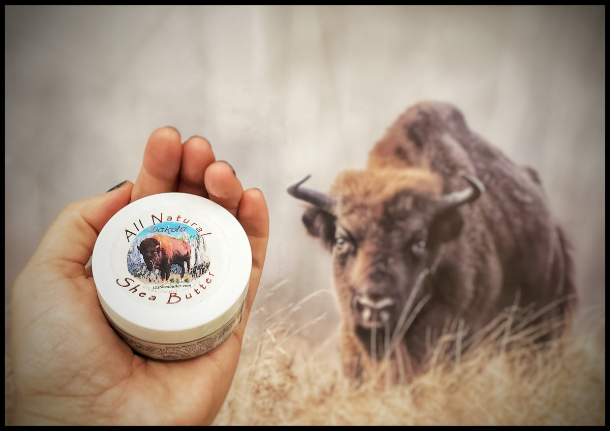 hand holding Dakota travel size jar in front of a photo of a Bison