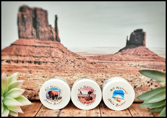 Shea butter 2oz jars of Dakota, Wild Bill's Heels and Unscented in front of photo of rocky outcrops from Monument Valley with green leaves on the sides