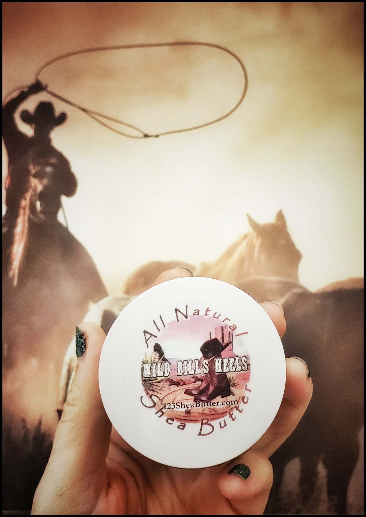 hand holding 2oz travel size jar of wild bill's Heels with photo of cowboy on Horse throwing a rope