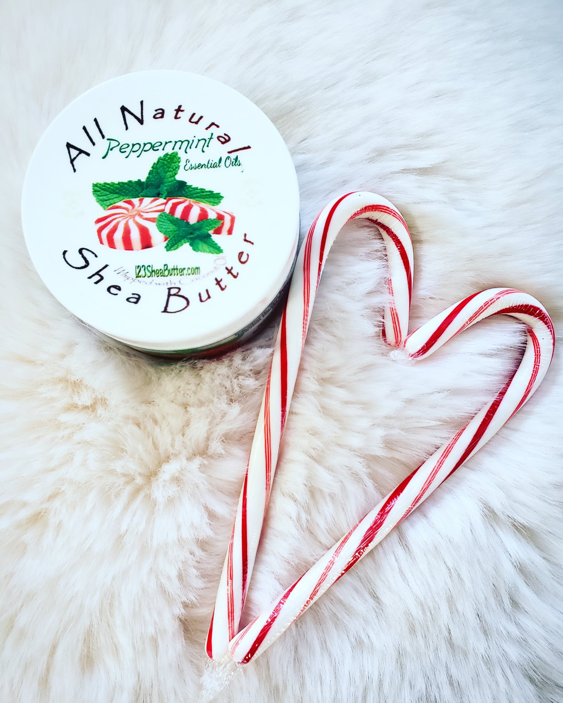Peppermint Shea butter jar with white background and two candy canes in the shape of a heart next to it